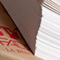 Fabriano drawing paper.  A close-up of a large stack of white paper sheets fanned out from a brown cardboard box with red printed text.