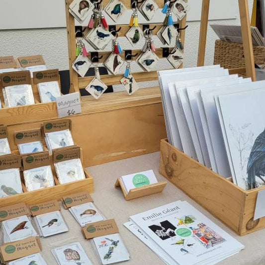 Table with various art prints and cards displayed on a stand.