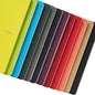 A collection of Fabriano Ecoqua Original stapled notebooks in various solid colors, displayed open to show the light ivory paper inside.